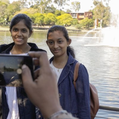 Harini (L) and Abinaya getting their photo taken in front of the UQ lakes.